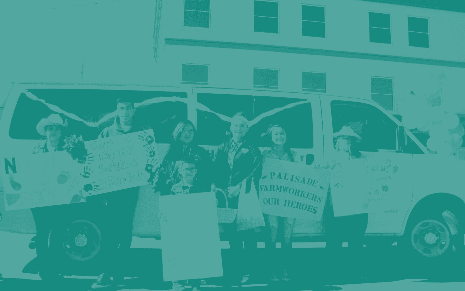 Staff and children stand in front of a white van holding hand-made signs reading Child Migrant Services Palisade CO and Palisade Farmworkers Our Heroes, in a one-color teal print